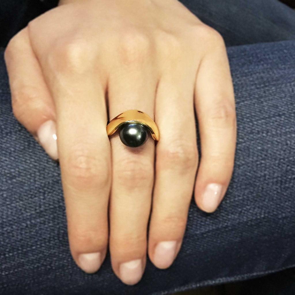 Pearl sling ring on hand. 12mm Dark grey tahitian pearl set in yellow gold