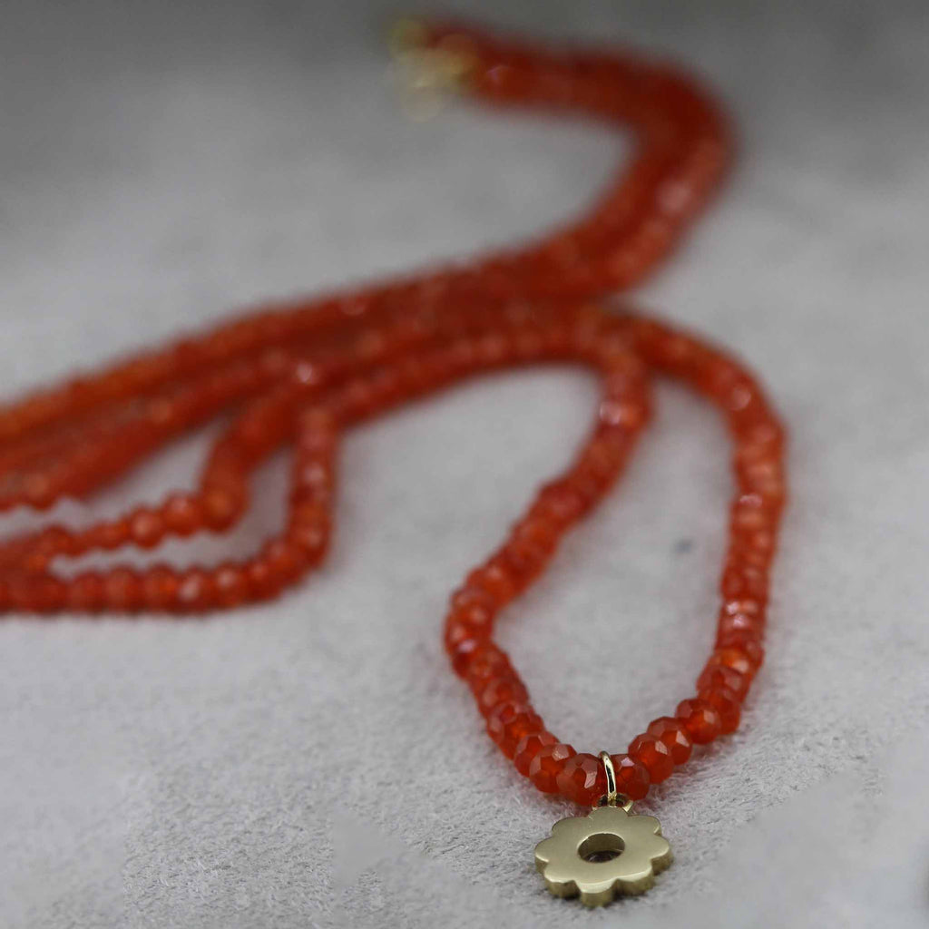 Carnelian gemstone necklace with gold daisy pendant.