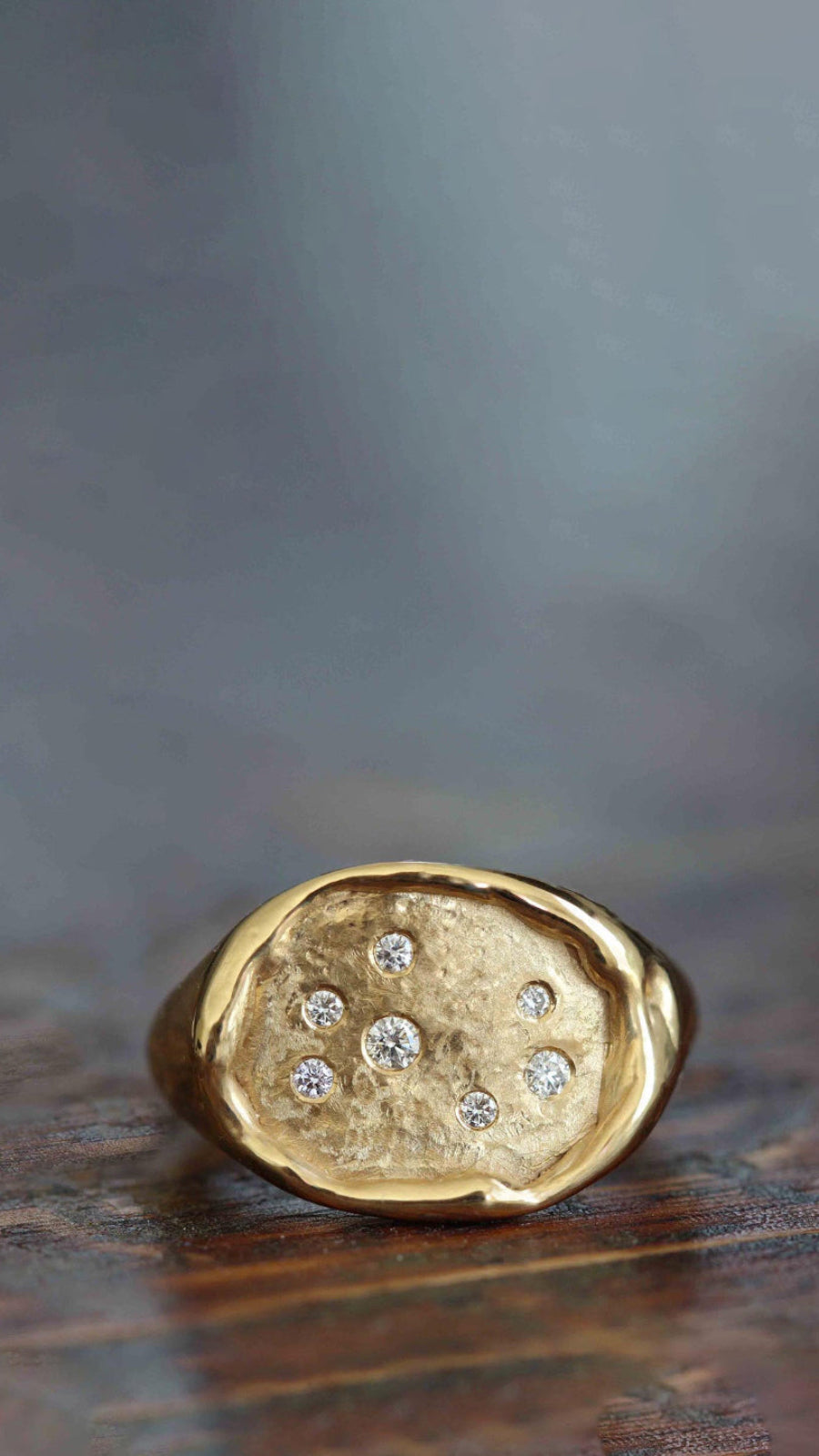Gold ring with embedded diamonds on a wooden surface