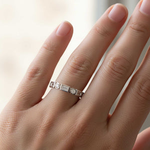 Platinum ring with gemstones on a person's finger against a blurred background
