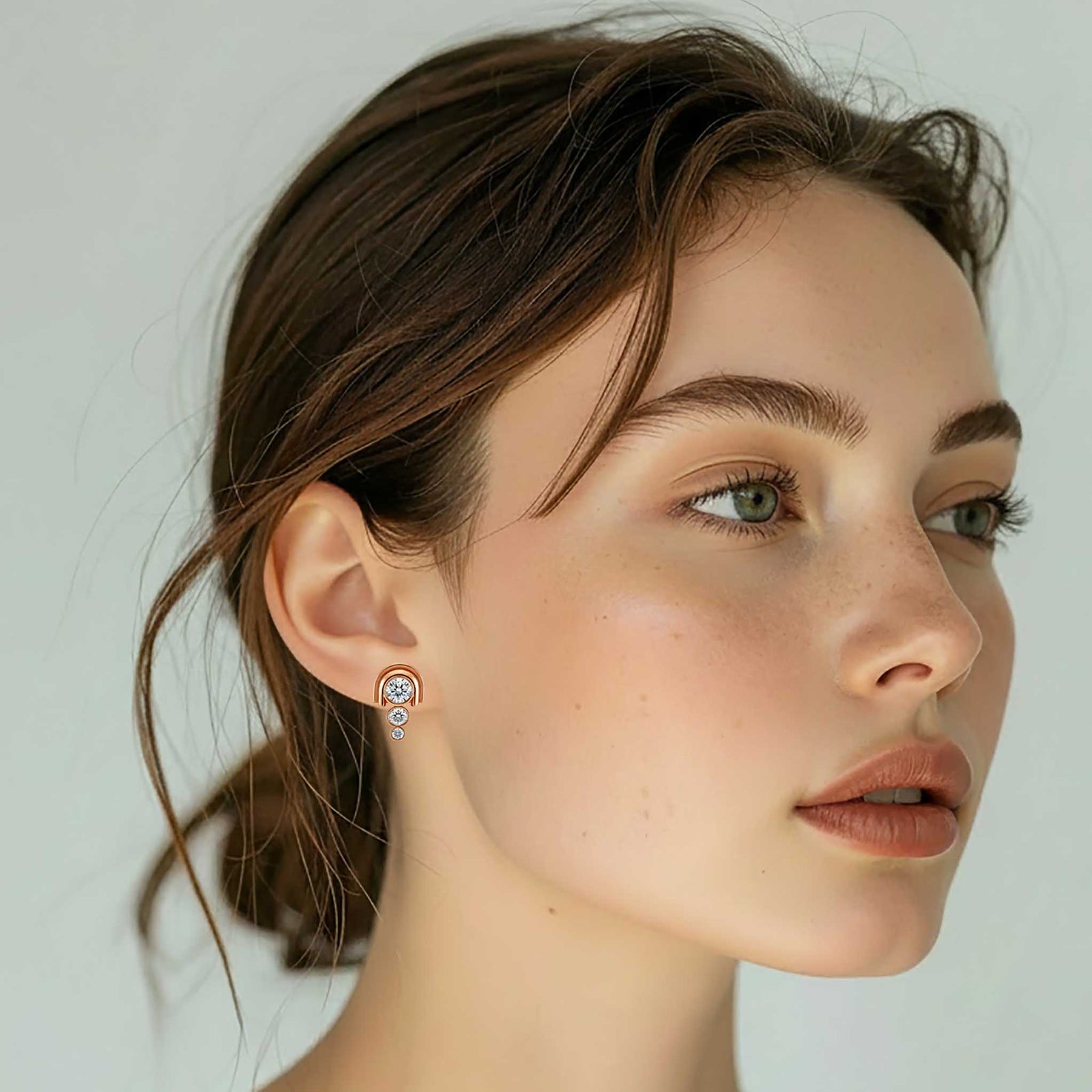 Rose gold earrings with clear gemstones on a white background