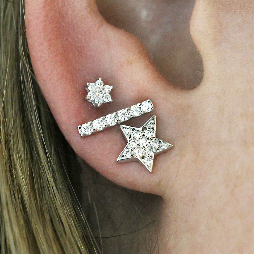 A group of white gold and diamond stud earrings on earlobe