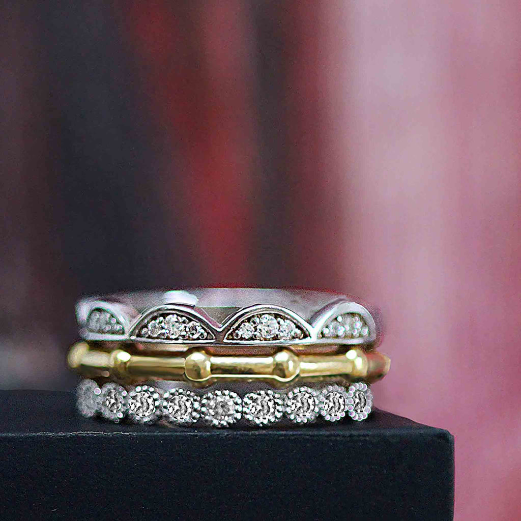 A stack of rings in white gold, yellow gold and diamonds. The Frill ring, the rib ring and the Blossom bud ring