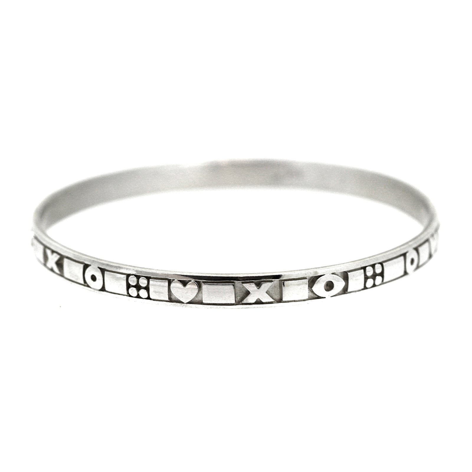 A sterling silver bangle with intricate design, featuring heart shapes and geometric patterns.